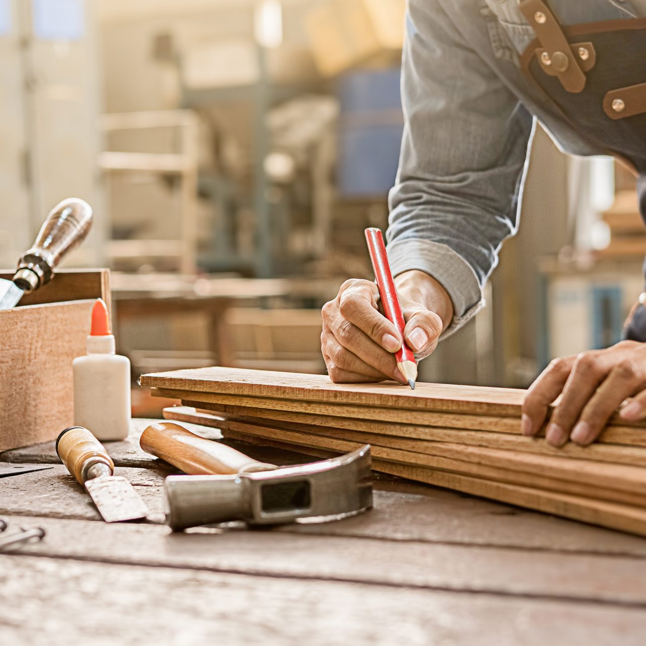 man marking up a bit of wood on a workshop bench