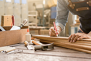 man marking up a bit of wood on a workshop bench